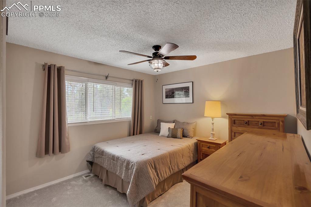 Image 22 of 41: Bedroom with a textured ceiling, light carpet, and a ceiling fan