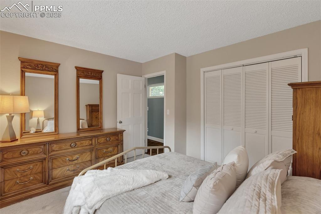 Image 28 of 41: Bedroom with a textured ceiling, a closet, and light colored carpet