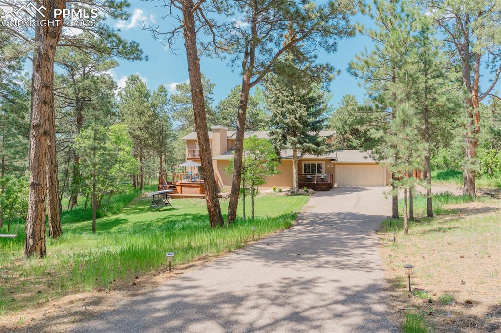 Image 36 of 41: View of front facade with driveway, a deck, stucco siding, a garage, and a