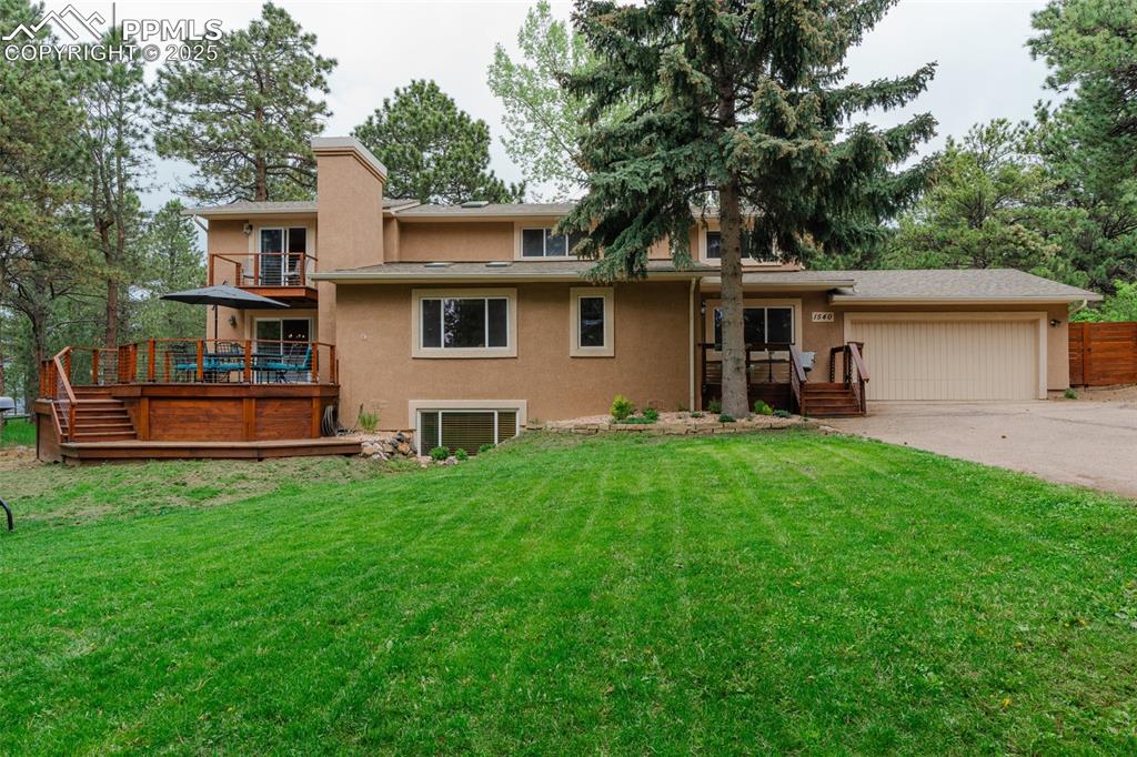 Image 37 of 41: Rear view of property featuring a yard, stucco siding, driveway, a garage,