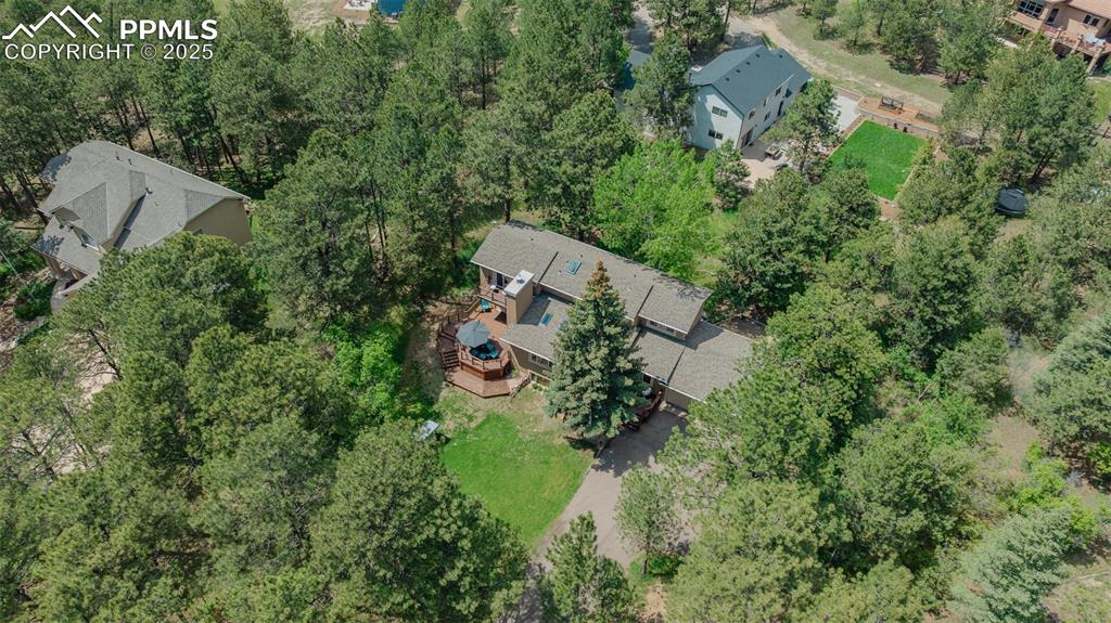 Image 38 of 41: Aerial view of property and surrounding area featuring a tree filled landsc