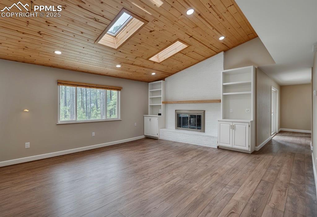 Image 5 of 41: Unfurnished living room featuring vaulted ceiling, recessed lighting, dark