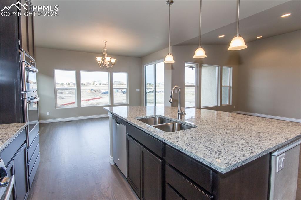 Image 10 of 28: Kitchen featuring a kitchen island with sink, dark wood-style floors, a sin