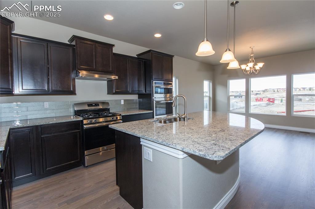 Image 11 of 28: Kitchen featuring a sink, tasteful backsplash, light stone countertops, und