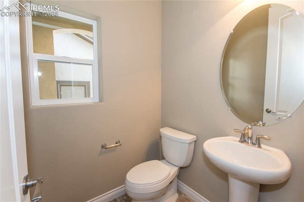 Image 14 of 28: Bathroom with toilet, a sink, and baseboards
