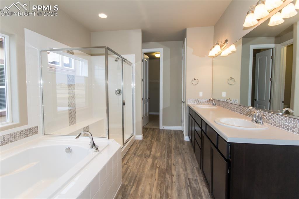 Image 18 of 28: Full bathroom with a bath, a shower stall, wood finished floors, and a sink
