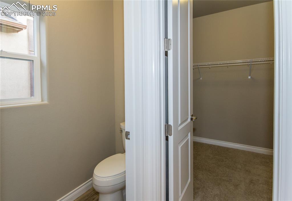 Image 19 of 28: Bathroom with baseboards, a spacious closet, and toilet