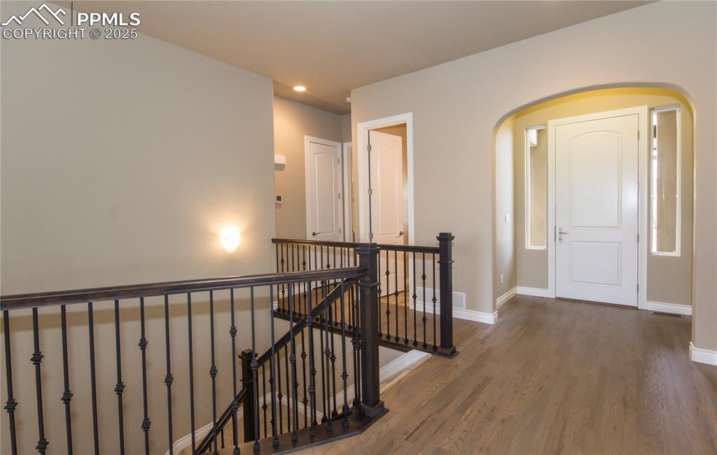 Image 3 of 28: Hallway featuring baseboards, wood finished floors, arched walkways, and an