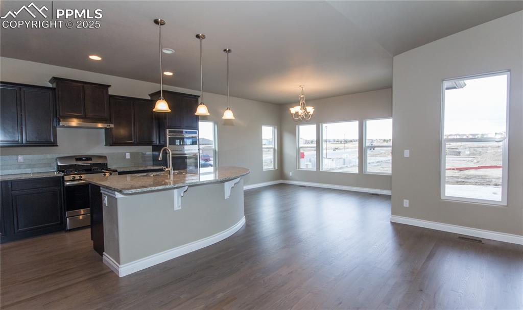 Image 4 of 28: Kitchen with an island with sink, a chandelier, stainless steel appliances,