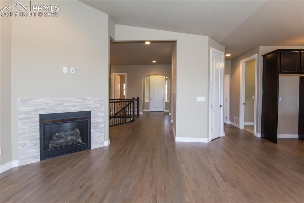 Image 6 of 28: Unfurnished living room featuring arched walkways, vaulted ceiling, visible