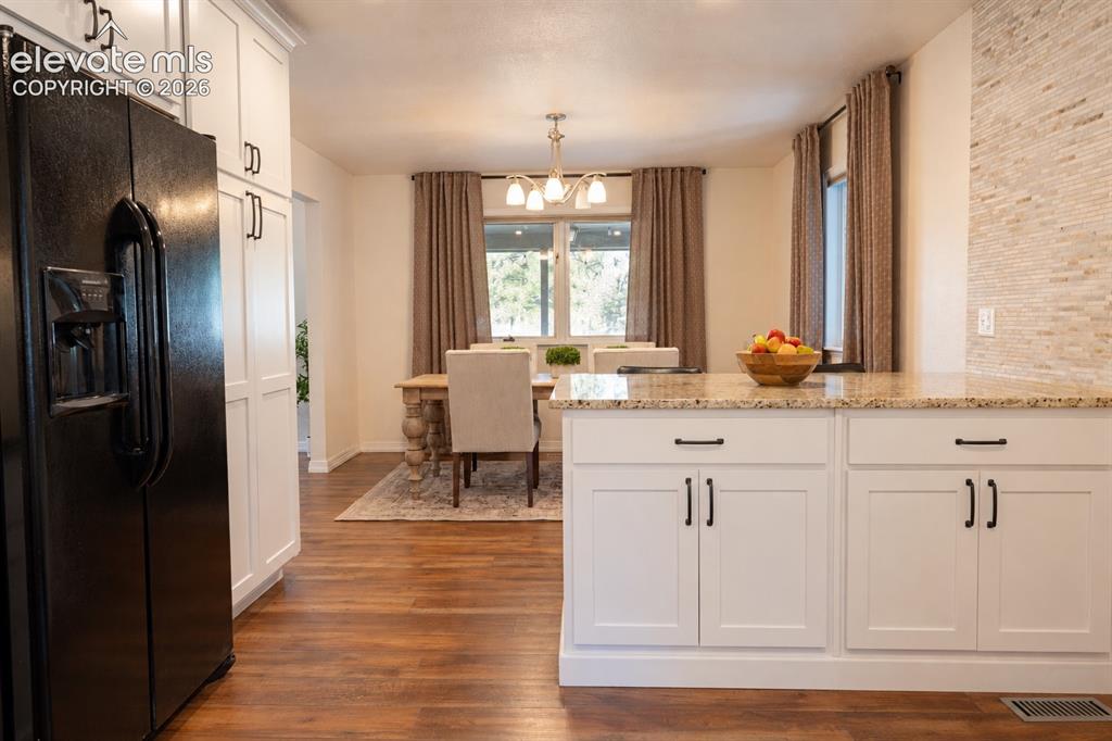Image 11 of 30: Kitchen featuring white shaker cabinetry, granite countertops, tile backspl