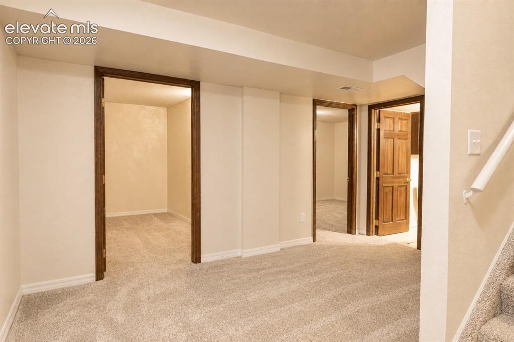 Image 19 of 30: Plush carpet flooring throughout, cream-colored walls, wood-finish door fra