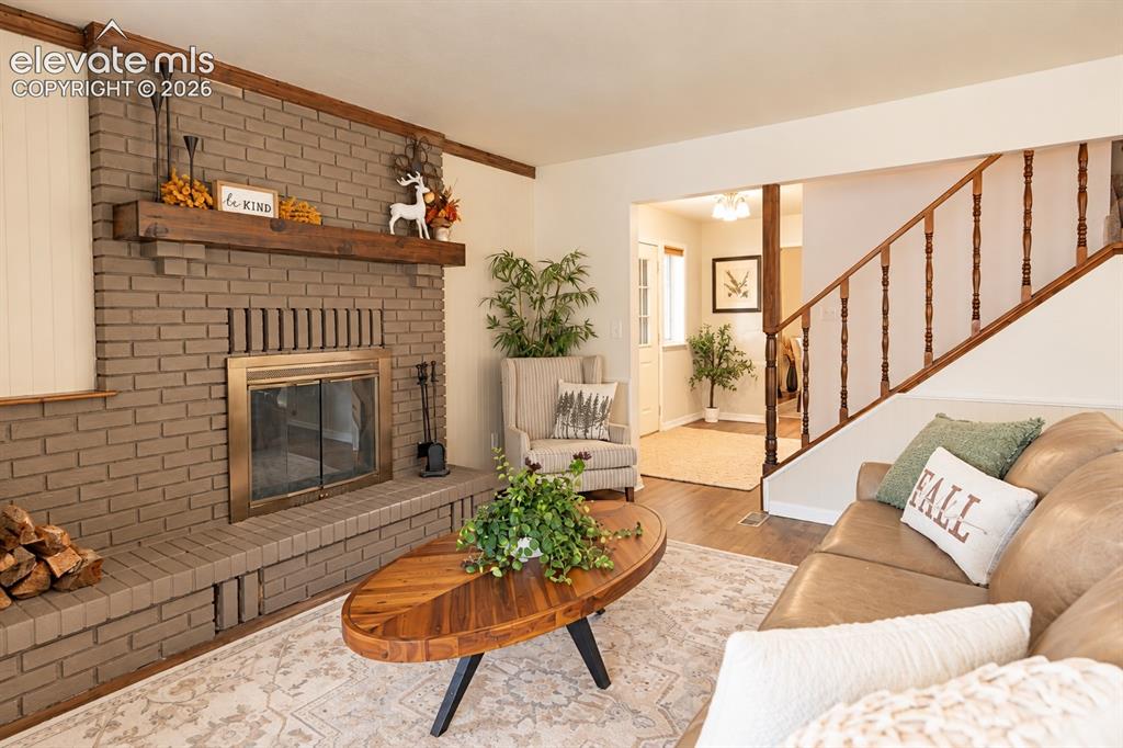 Image 2 of 30: Brick fireplace with a wood mantle, brass-framed glass doors, and a hearth