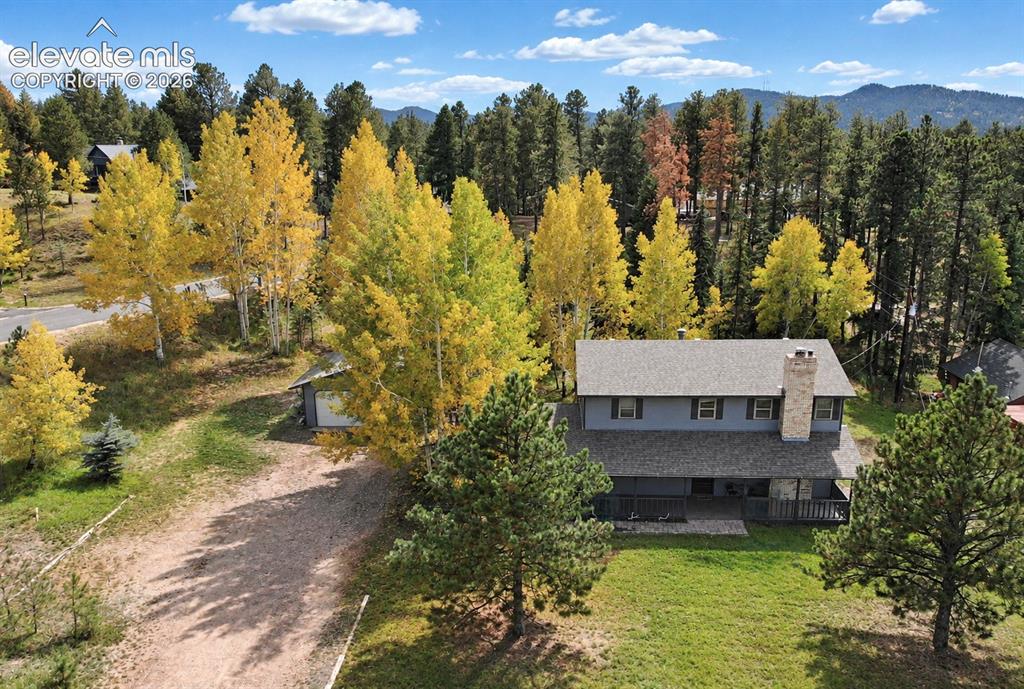 Image 22 of 30: Expansive exterior with a gray-sided residence, stone chimney, and a dark-c