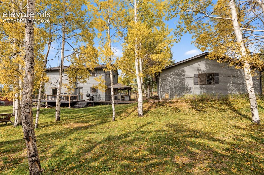 Image 25 of 30: Expansive green lawn with mature trees, a two-story residence with a multi-