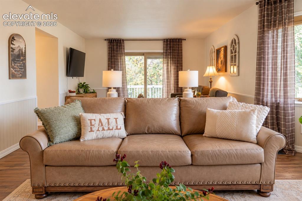 Image 5 of 30: Living area featuring wood-finish flooring, wainscoting, and a sliding glas