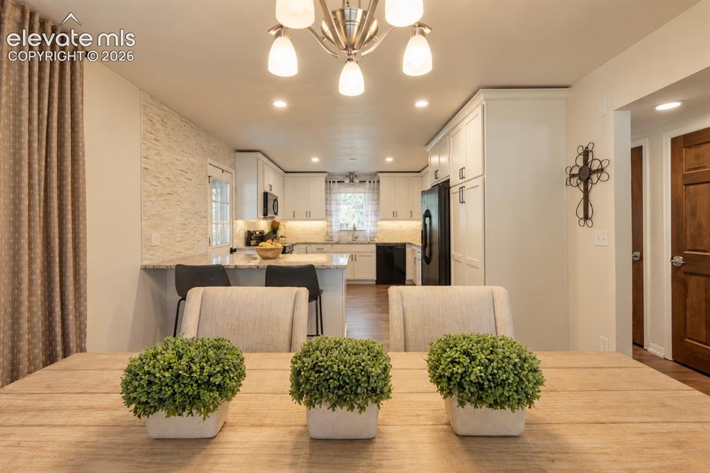 Image 8 of 30: Open-concept kitchen featuring white cabinetry, black appliances, recessed 