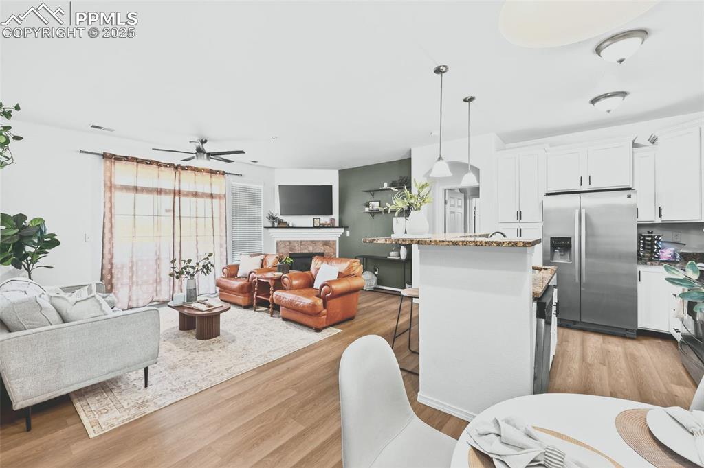 Image 10 of 25: Living room with light wood finished floors, a ceiling fan, and a high end 