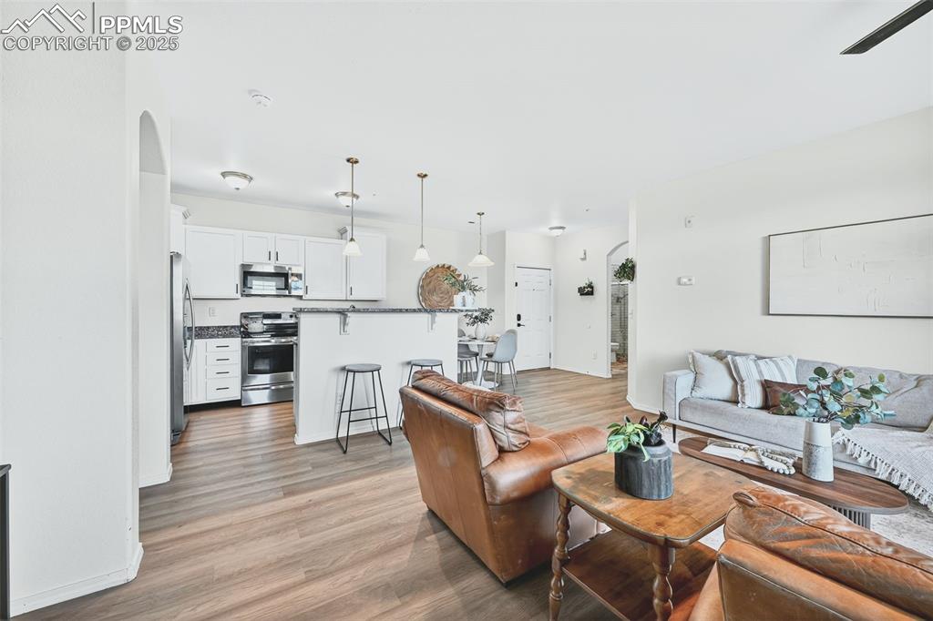 Image 11 of 25: Living room with arched walkways and light wood-style floors