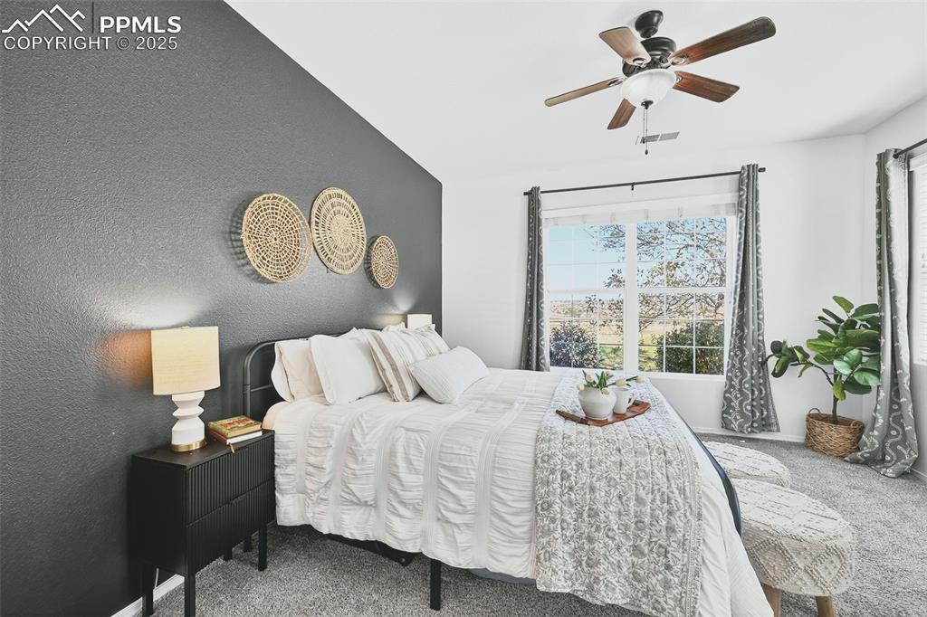 Image 15 of 25: Bedroom with carpet flooring, a textured wall, and ceiling fan