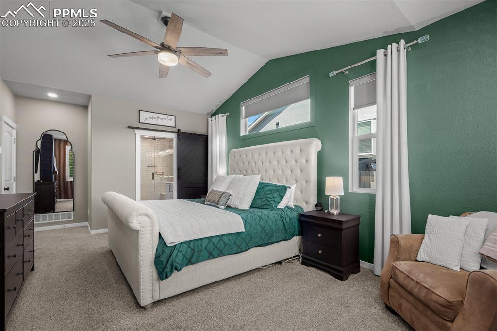 Image 17 of 37: Bedroom featuring a barn door, light colored carpet, lofted ceiling, a ceil