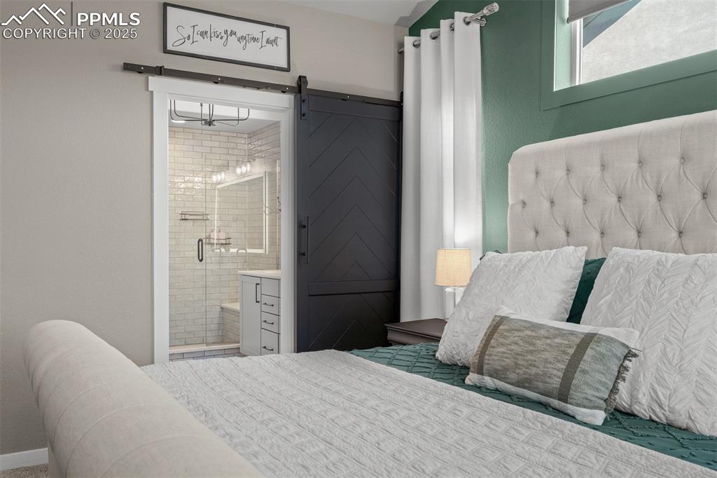 Image 19 of 37: Bedroom featuring a barn door and connected bathroom