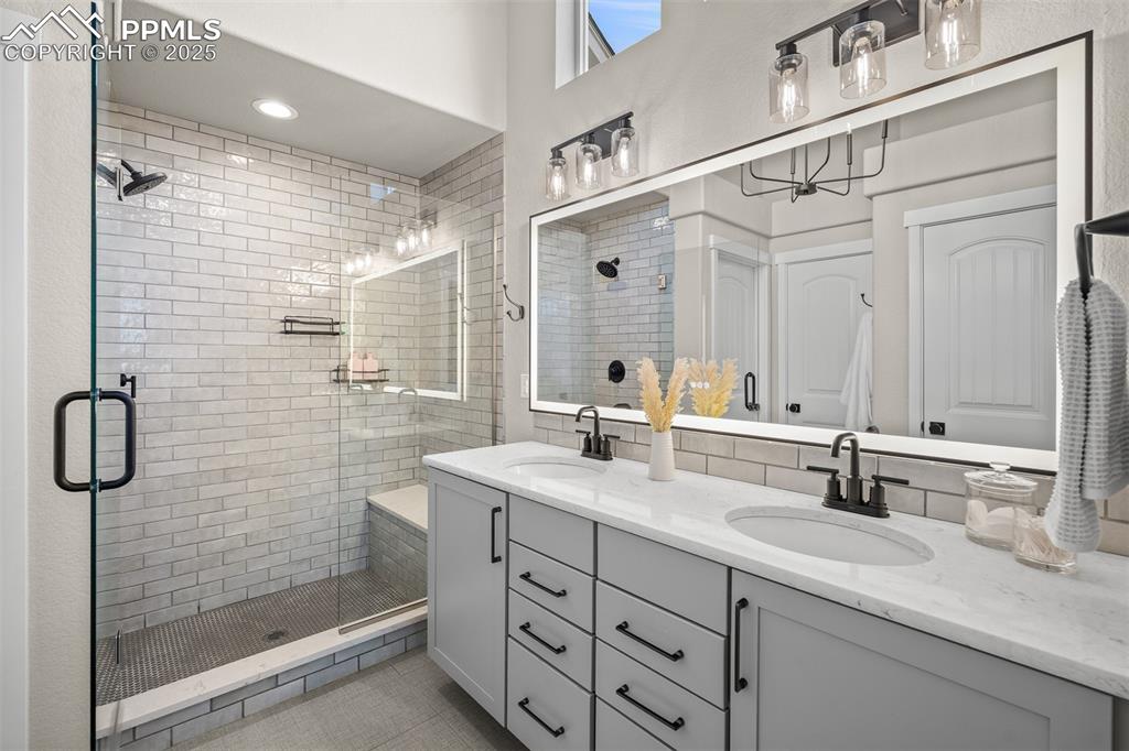 Image 21 of 37: Full bath featuring a stall shower, double vanity, and light tile patterned