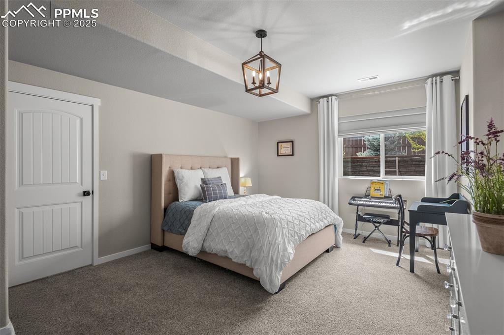 Image 31 of 37: Carpeted bedroom with baseboards and a chandelier
