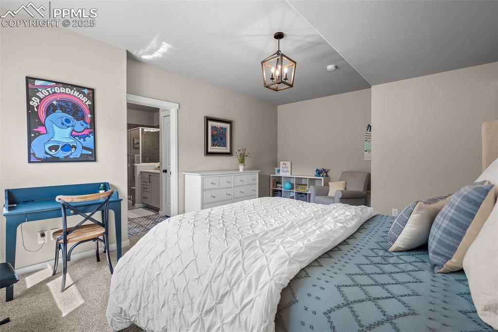 Image 32 of 37: Bedroom with carpet flooring, connected bathroom, and a chandelier