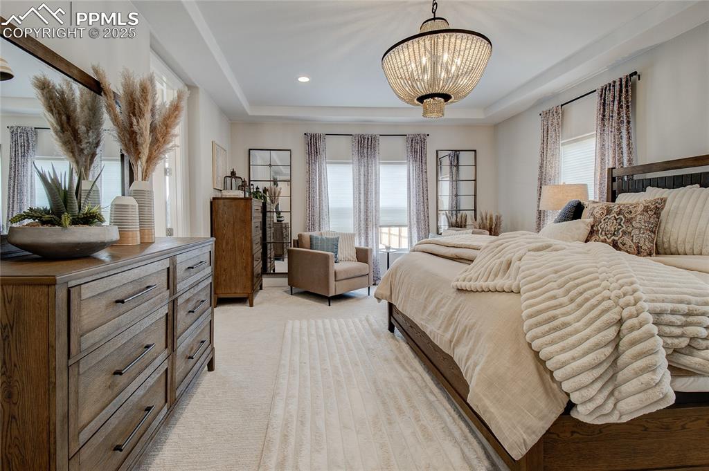 Image 15 of 29: Bedroom featuring a tray ceiling, light carpet, recessed lighting, and a ch