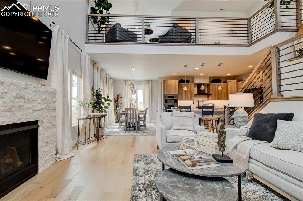 Image 2 of 29: Living room featuring a high ceiling, light wood finished floors, a stone f