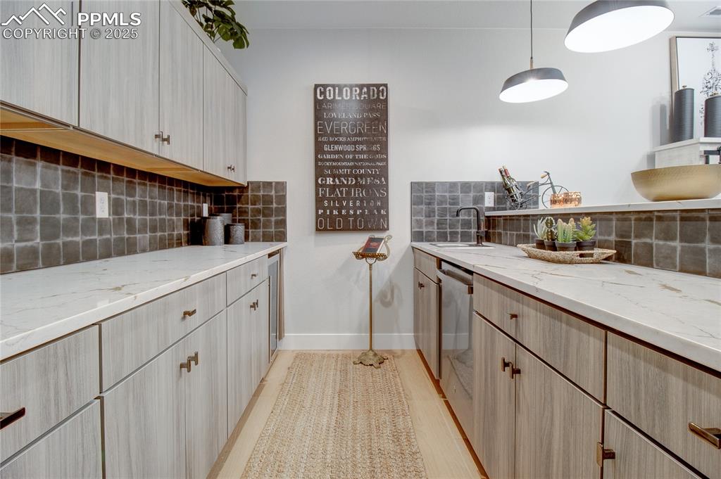 Image 26 of 29: Kitchen with tasteful backsplash, light stone counters, stainless steel dis