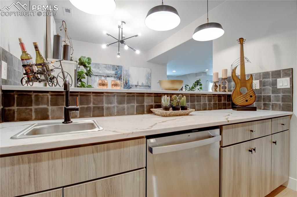 Image 27 of 29: Kitchen with light brown cabinets, stainless steel dishwasher, and tasteful