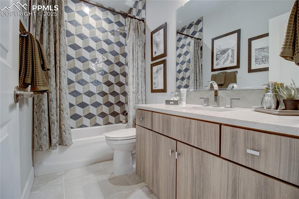 Image 28 of 29: Bathroom featuring vanity, shower / bath combo with shower curtain, and til