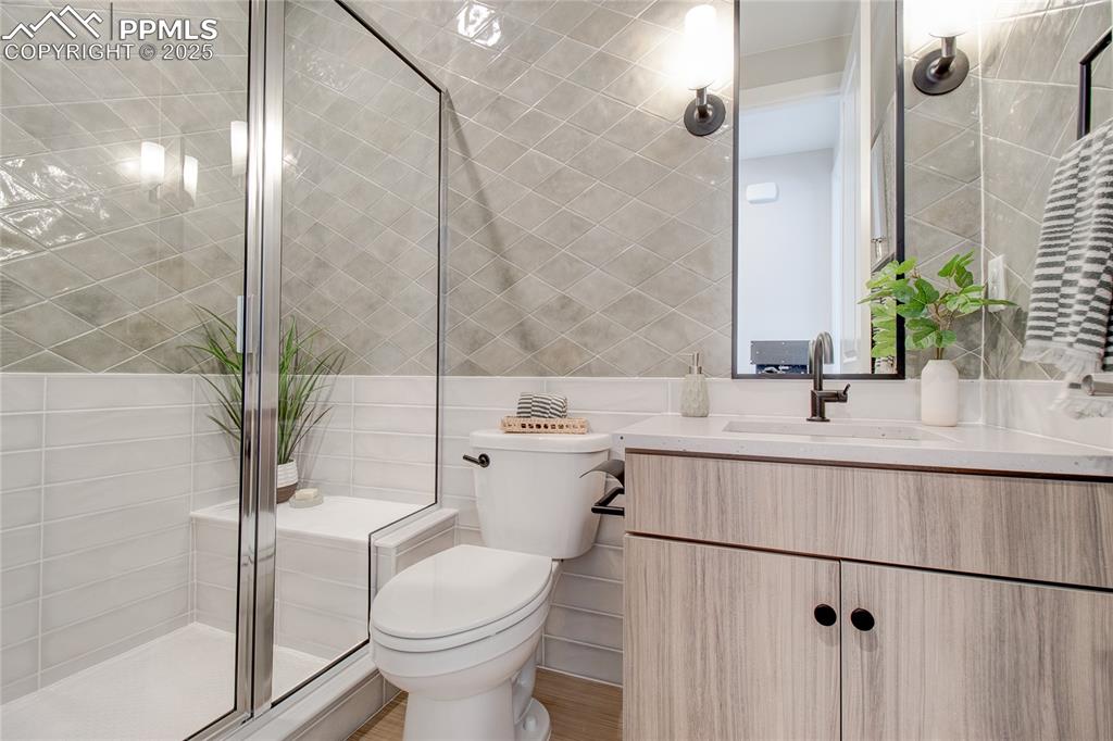Image 4 of 29: Full bath featuring tile walls, vanity, and a shower stall