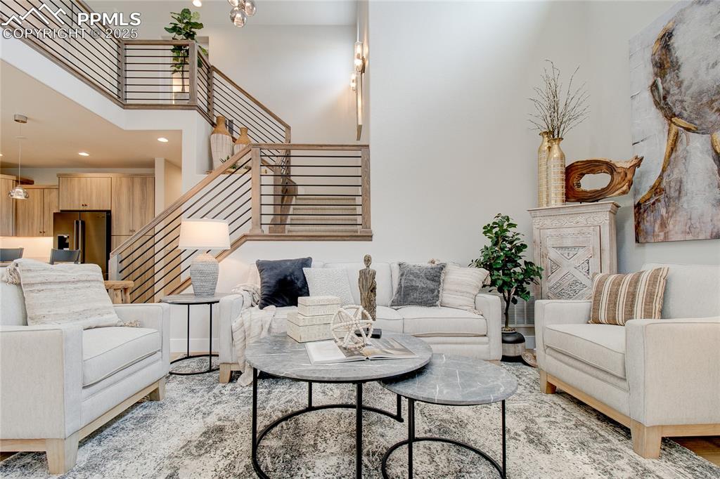 Image 5 of 29: Living room featuring a high ceiling, stairs, recessed lighting, and a chan