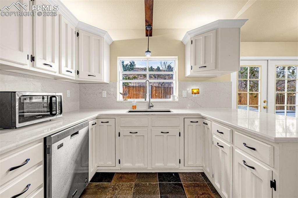 Image 14 of 50: Kitchen with white cabinets, appliances with stainless steel finishes, deco