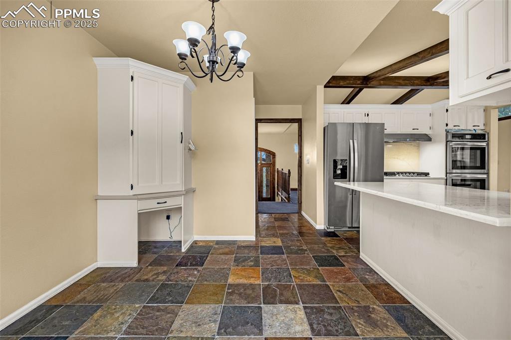 Image 15 of 50: Kitchen with stone tile flooring, stainless steel appliances, hanging light