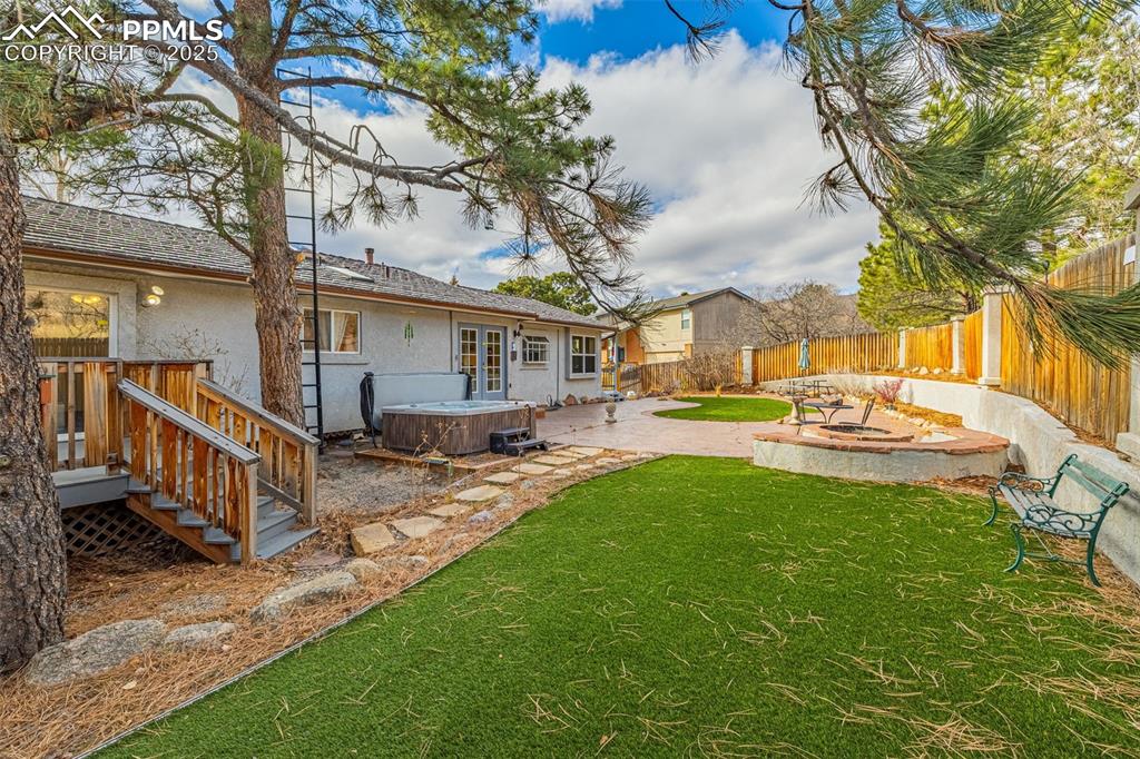Image 29 of 50: Fenced backyard with a hot tub and a patio area