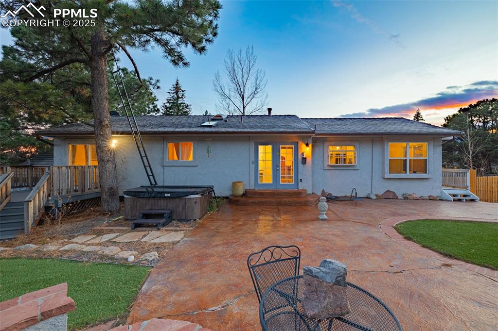 Image 31 of 50: Rear view of property featuring a hot tub, stucco siding, a patio, and a de