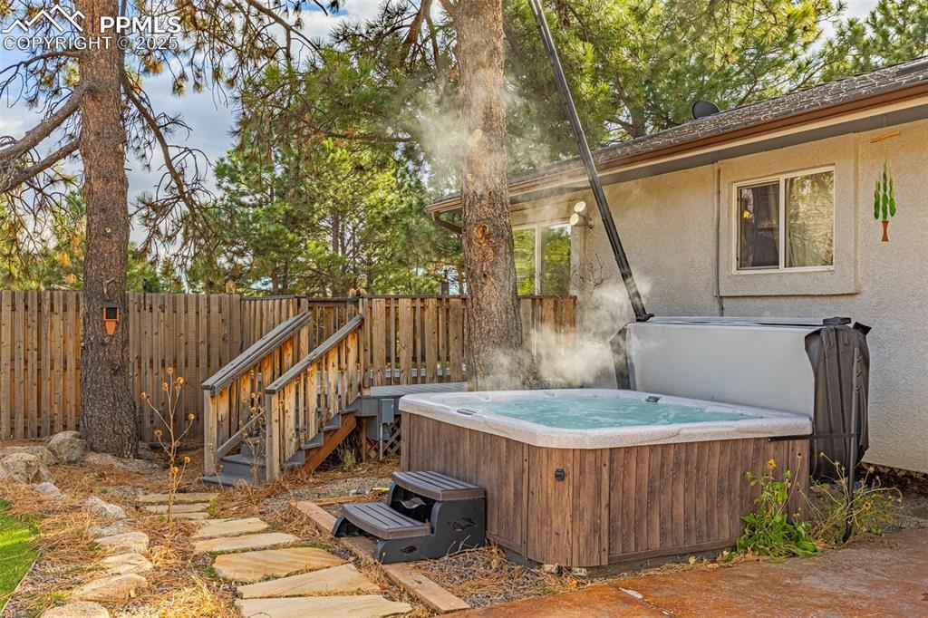 Image 36 of 50: Trex deck featuring a hot tub and a fenced backyard
