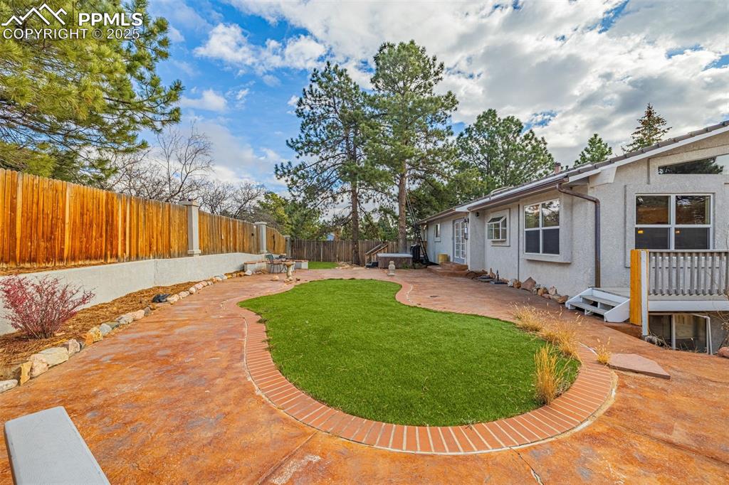 Image 37 of 50: Fenced backyard with a patio