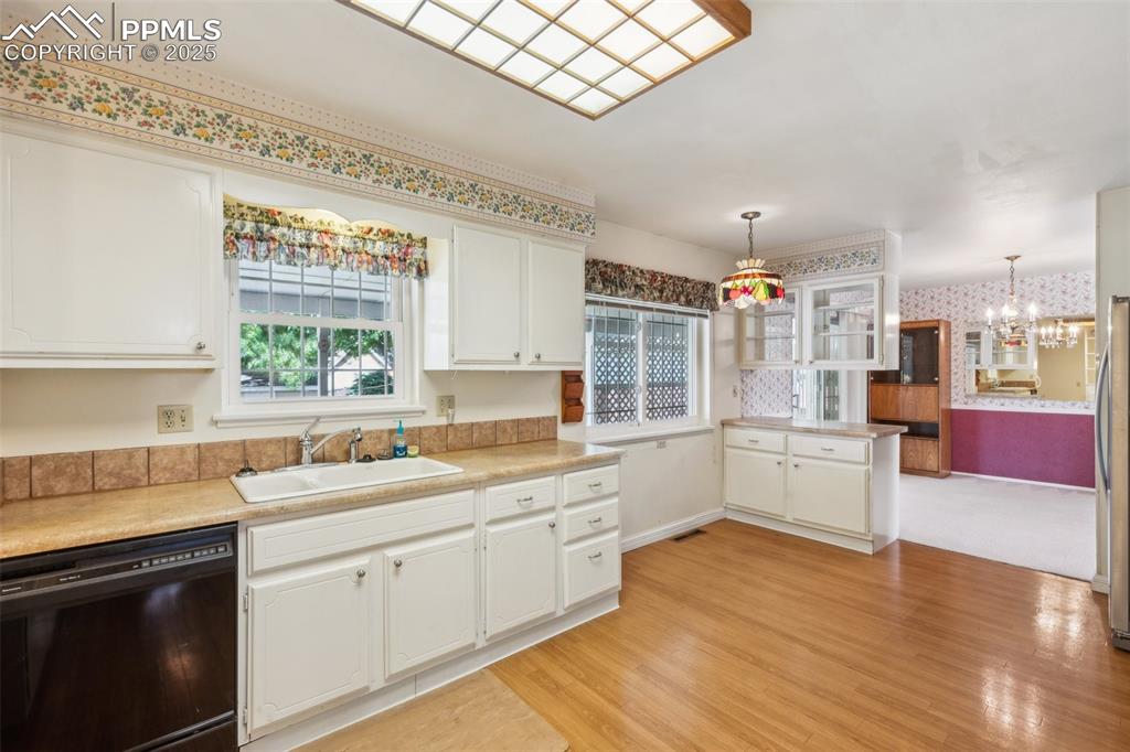 Image 14 of 30: Kitchen featuring black dishwasher, wallpapered walls, a chandelier, white