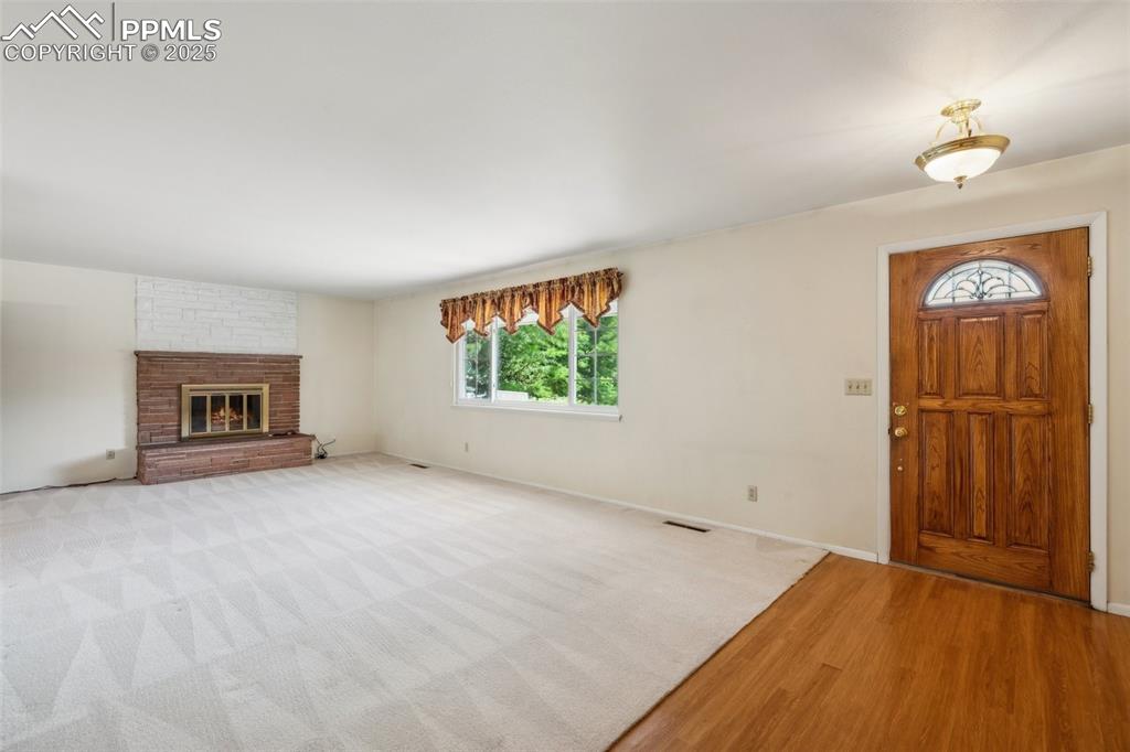 Image 15 of 30: Entrance foyer with wood finished floors and a fireplace