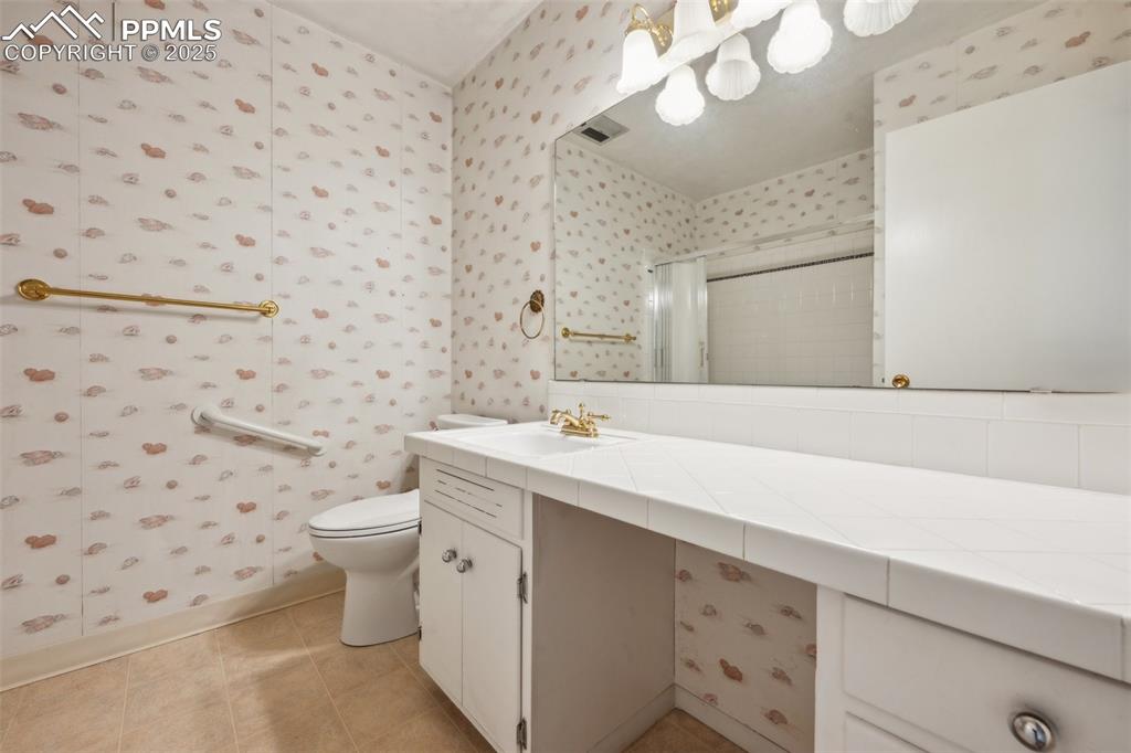 Image 16 of 30: Full bath featuring wallpapered walls, vanity, a shower stall, and tile pat