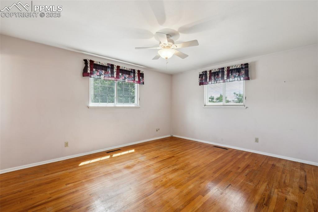 Image 17 of 30: Empty room with a ceiling fan and wood finished floors