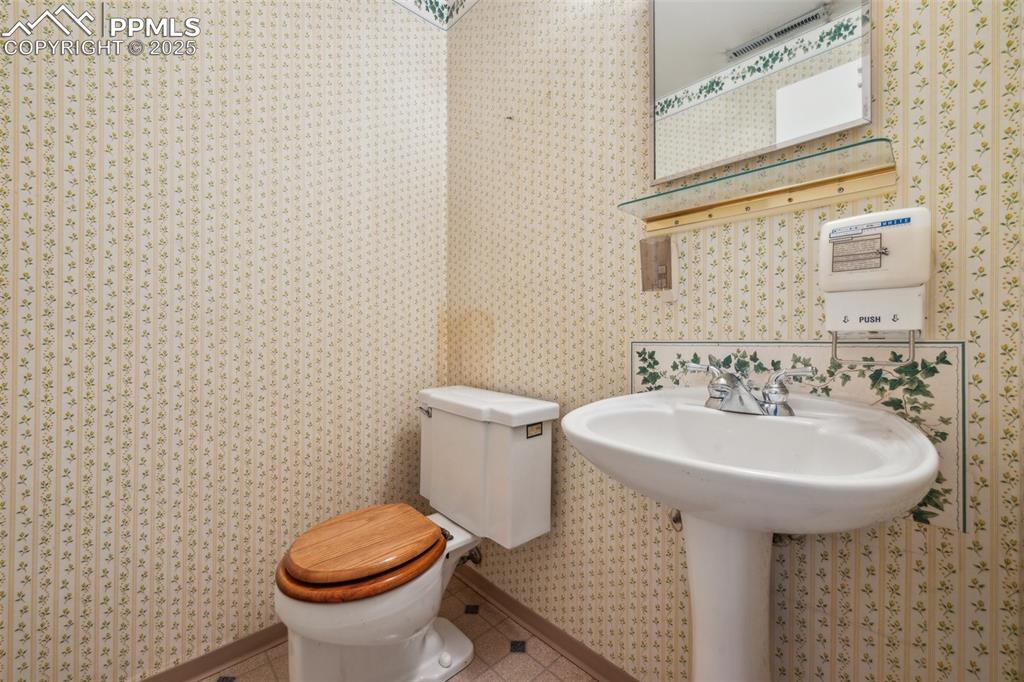 Image 24 of 30: Half bathroom with wallpapered walls and toilet