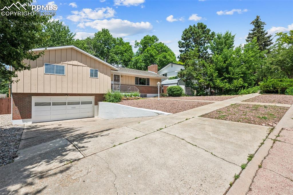Image 3 of 30: View of front of house featuring driveway, a garage, brick siding, and boar