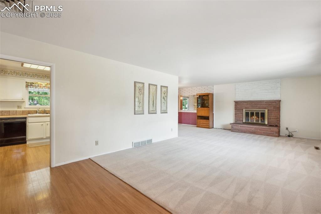 Image 6 of 30: Unfurnished living room with a fireplace and light wood-style floors