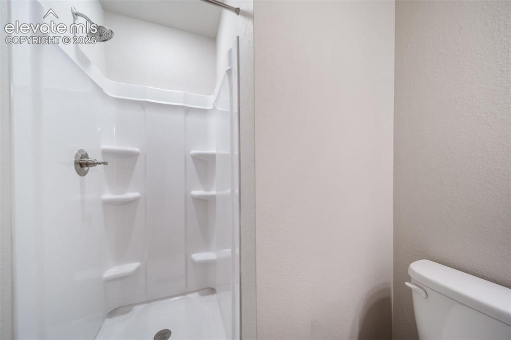 Image 10 of 18: Shower stall with integrated shelving, brushed nickel fixtures, and a white